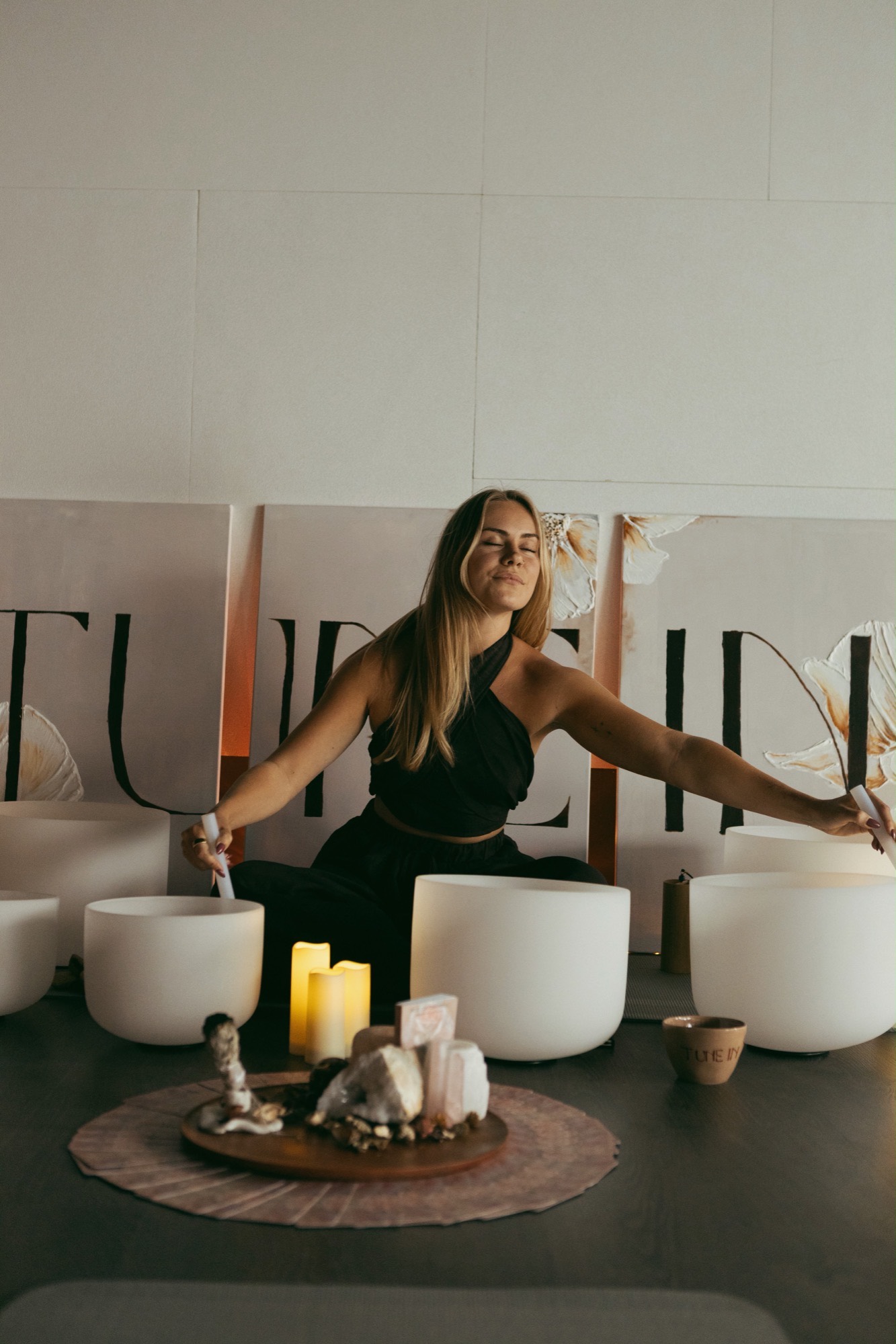 Sem with arms outstretched over crystal singing bowls during a private sound healing session